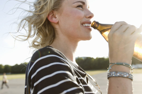 Mid adult woman drinking bottled beer outdoors