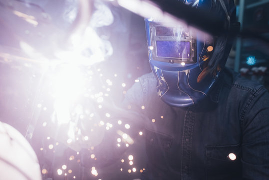 Mature man in garage, working on motorcycle, using welding equipment