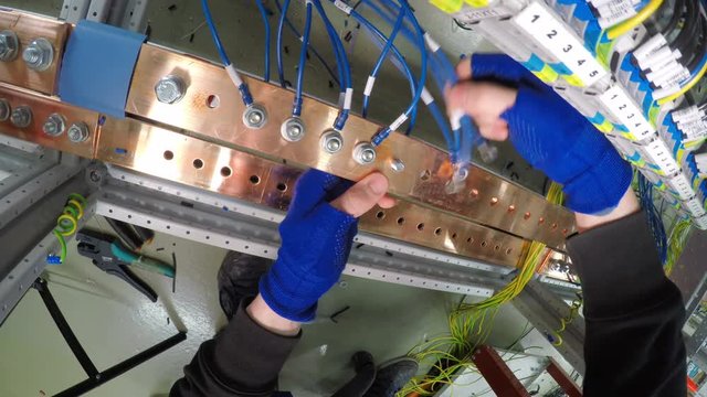 Professional electrician installing cables into electical box control cabinet into fuse box. 4K.