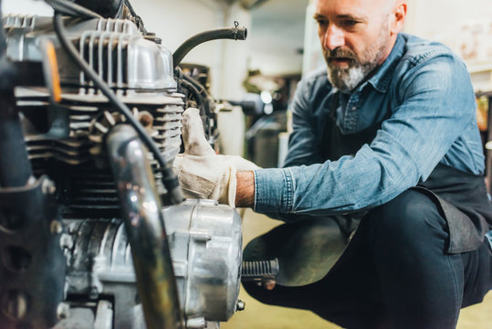 Mature man, working on motorcycle in garage