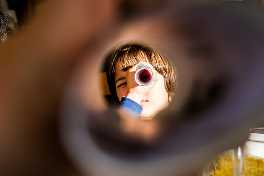 Portrait of boy looking at camera through rolled paper