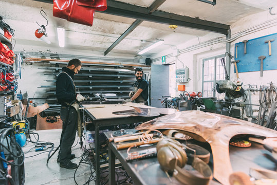Two metalworkers working at forge workbench