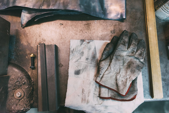 Overhead view of metals and protective gloves on forge workbench