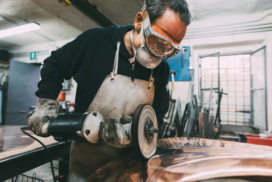 Metalworker polishing copper in forge workshop