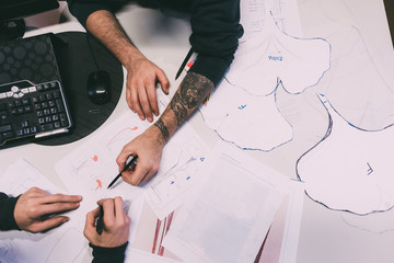 Overhead view of two male metalworkers designing in forge office