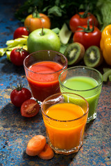 assortment of fresh vegetable juices on a blue background, vertical