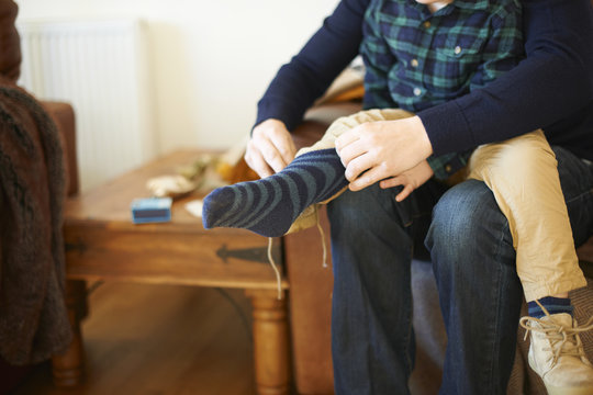 Adult helping child wear socks