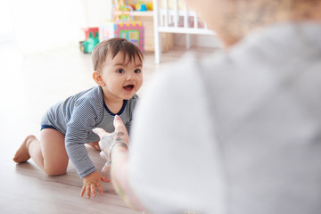 Mother watching baby son crawl towards her