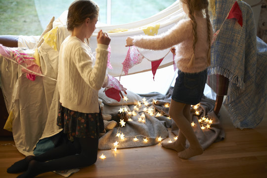 Two sisters in bedroom den hanging bunting and star shape lights