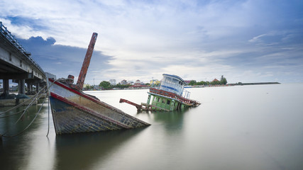 A sinking wood ship in a smooth surface of river and beautiful sky