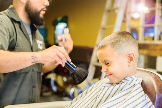 Barber cleaning boy's face with brush