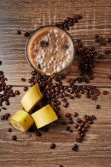 Coffee and banana smoothie in a glass on a wooden background