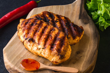 Grilled chicken breast on wooden cutting board