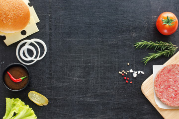 Homemade minced beef, sesame bun, onion, tomato, lettuce, BBQ sauce. Hamburger ingredients on a black background. Space for text.