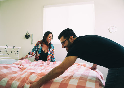 Happy couple making bed together