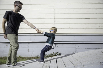 Boy pulling father up wooden ramp