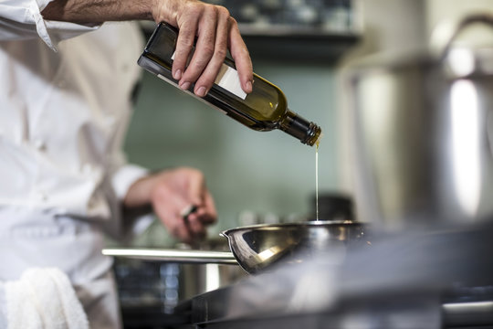 Chef pouring oil into frying pan