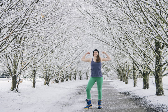 Portrait of woman flexing muscles, in snow covered rural landscape