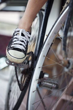 Person riding a vintage bicycle, close up view of sneaker shoe and the pedal