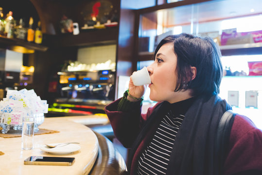 Young beautiful caucasian woman having a coffee in a bar - relaxing, drinking concept