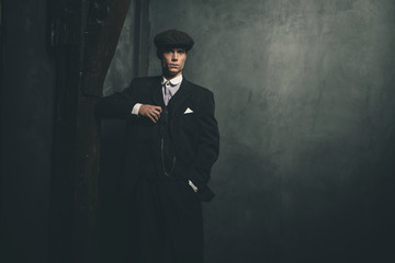 Retro 1920s english gangster wearing suit and flat cap.