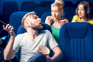 Rude man talking with phone disturbing women on the back seats in the cinema