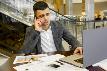 Fototapeta premium Portrait of successful young businessman talking on mobile phone