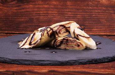 crepe with banana and chocolate on round slate stand