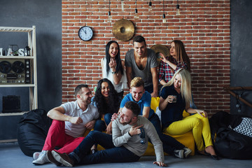 Group portrait of multi-ethnic boys and girls with colorful fashionable clothes holding friend posing on a brick wall, Urban style people having fun, Concepts about youth togetherness lifestyle