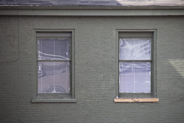 Two rectangular windows on a gray brick wall.