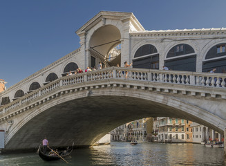 Fototapeta na wymiar A gondola passes under the Rialto Bridge of Venice, Italy