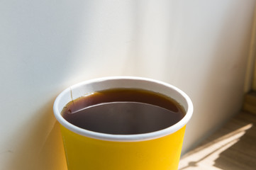 Close up hot black coffee cup on wood table top at coffee shop window.
