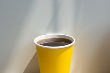 Close up hot black coffee cup on wood table top at coffee shop window.