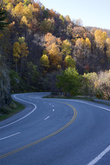 Beautiful downhill S curve winding through colorful autumn hillside.