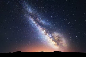 Raamstickers Milky Way. Fantastic night landscape with bright milky way, sky full of stars, yellow city light and mountains. Picturesque scene with our universe. Space background. Amazing astrophotography © den-belitsky