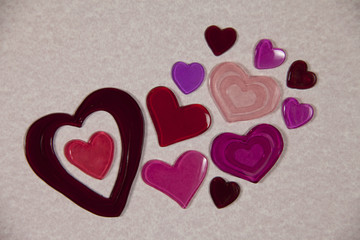 Several colorful gel hearts on pink textured background.