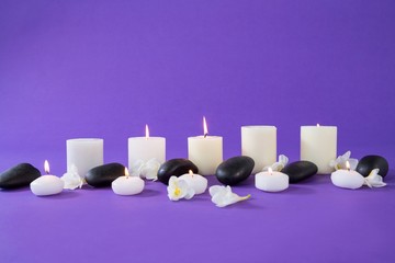 Candles, flowers and zen stones on purple background