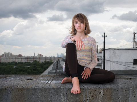 Teenage girl sitting high on the roof of the house