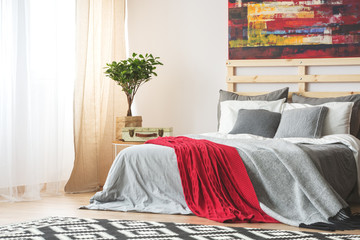 Grey bed with red blanket - obrazy, fototapety, plakaty