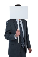 Businessman covering his face behind blank placard