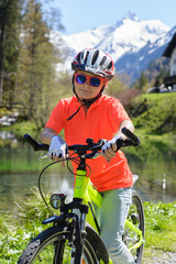 Smiling little girl riding a bike in a beautiful mountain landscape