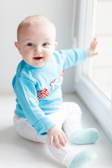 Laughing baby sitting on the windowsill