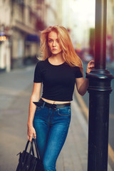 Street style. Beautiful woman walks on the street at the Moscow City at sunny spring day.