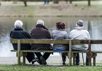 Vier Senioren sitzen auf einer Parkbank 