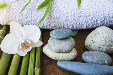 spa concept/orchid flower,bamboo stems, stones, towel on a wet wooden background