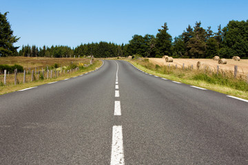 route déserte au milieu des champs et meules de foin