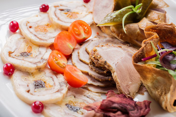 Meat plate with delicious pieces of sliced ham, cherry tomatoes, herbs and meat with cranberry. Close up with selective focus