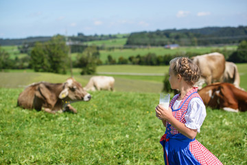 Adorable  bavarian girl drinking milk on the farm in Germany .