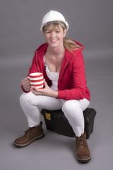 Woman worker wearing a hard hatand holding a mug