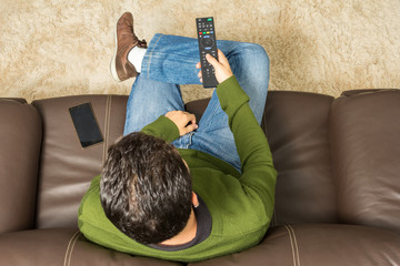 Man watches television. Overhead view, brown couch.